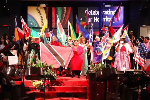 Flag bearers representing different countries stand at the front of Metropolitan Seventh-day Adventist Church after processing into the sanctuary for "Caribbean Sabbath" at the Hyattsvile, Md., church on Saturday, Feb. 18, 2023. (Adelle M. Banks/RNS via AP)