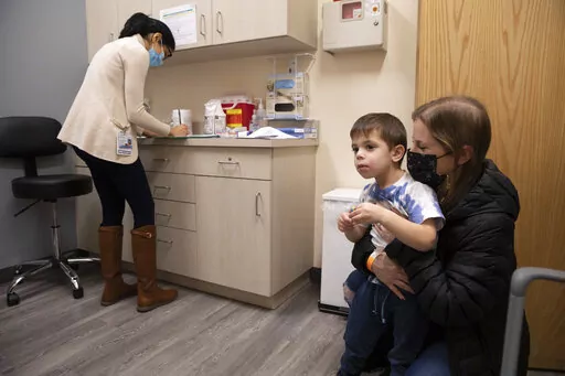 Ilana Diener holds her son, Hudson, 3, during an appointment for a Moderna COVID-19 vaccine trial in Commack, N.Y. on Nov. 30, 2021. On Wednesday, March 23, 2022, Moderna said its COVID-19 vaccine works in babies, toddlers and preschoolers, and if regulators agree it could mean a chance to finally start vaccinating the littlest kids by summer. (AP Photo/Emma H. Tobin)
