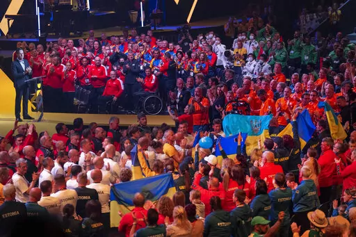 Dutch Prime Minister Mark Rutte, left, athletes and the audience gave a long standing ovation to the team from Ukraine, center with blue and yellow flags, during the opening ceremony of the Invictus Games venue in The Hague, Netherlands, Saturday, April 16, 2022. The week-long games for active servicemen and veterans who are ill, injured or wounded opens Saturday in this Dutch city that calls itself the global center of peace and justice. (AP Photo/Peter Dejong)