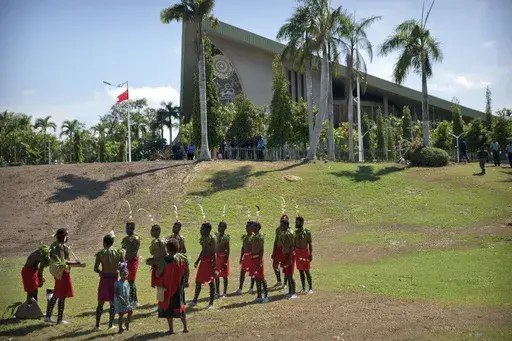 Performers in traditional dresses stand outside of Parliament Haus in Port Moresby, Papua New Guinea, on Nov. 16, 2018. At least 26 people has been reported killed by a gang of men in three remote villages last week in Papua New Guinea's north, United Nations and police officials said on Wednesday, July 24, 2024. (AP Photo/Mark Schiefelbein, FILE)