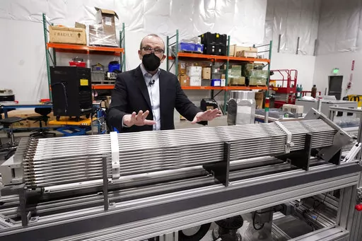 Chris Levesque, president and CEO of TerraPower, a company developing and building small nuclear reactors, displays a fuel assembly model, Thursday, Jan. 13, 2022, in Everett, Wash. The 5-foot model is about one-third actual length and would be vertical when in use, rather than horizontal. By cooling the reactor with liquid sodium, a metal that solidifies at well above room temperature, TerraPower says its relatively small, 345-megawatt plant will be safe and less expensive than conventional, wa