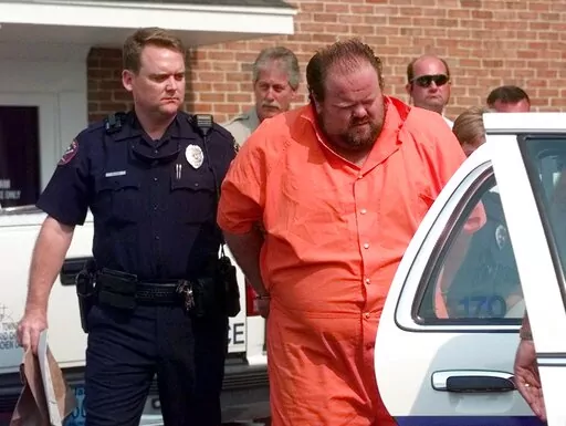 Officials escort murder suspect Alan Eugene Miller away from the Pelham City Jail in Ala., on Aug. 5, 1999. Miller, scheduled to be put to death by lethal injection on Sept. 22, 2022, for a workplace shooting rampage in 1999 that killed three men, says the state lost the paperwork he turned in selecting an alternate execution method. (AP Photo/Dave Martin, File)