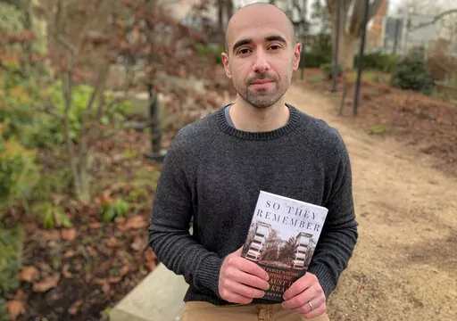 Author Maksim Goldenshteyn poses with his book "So They Remember" in Seattle, U.S., Saturday, Jan. 29, 2022. Maksim Goldenshteyn's book, “So They Remember,” tells the story of his Holocaust survivor grandparents who languished in Jewish death camps and ghettos in Transnistria during World War II — a chapter of the Holocaust which some say is largely forgotten. (Maksim Goldenshteyn via AP)