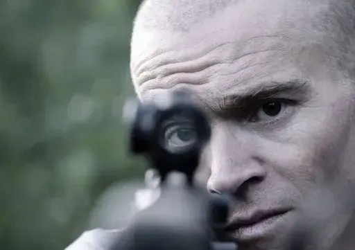 In this photo provided by Neon, former U.S. Green Beret Jordan Goudreau holds an assault rifle in this undated photo from a documentary film being made about the combat veteran's involvement in a coup attempts against Venezuelan President Nicolas Maduro. (Neon via AP)