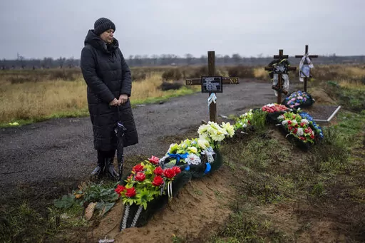 Svetlana Shornik stands next to the grave of her 53-year-old ex-husband, Oleh Shornik, on the outskirts Kherson, Ukraine, on Sunday, Nov. 20, 2022. Oleh Shornik was among 20 civilian volunteers of Ukraine’s Territorial Defense Forces killed by Russian troops in March in the southern city before it fell to Moscow. Russia held it for eight months before retreating in November. (AP Photo/Bernat Armangue)