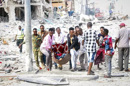 Rescuers remove a seriously-injured body from the scene of a double car-bomb attack in the capital Mogadishu, Somalia Saturday, Oct. 29, 2022. Two car bombs exploded Saturday at a busy junction in Somalia's capital near key government offices, leaving "scores of civilian casualties," police told state media. (AP Photo/Farah Abdi Warsameh)