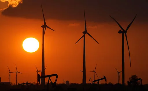 FILE -Wind turbines produce power during sundown in Emlichheim, Germany, Friday, March 18, 2022. The head of the International Renewable Energy Agency says “radical action” is needed to ensure global warming doesn't pass dangerous thresholds, warning that greenhouse gas emissions are heading in the wrong direction.(AP Photo/Martin Meissner,file)