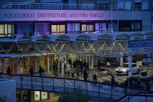 People walk in front of the main entrance of the Agostino Gemelli Polyclinic in Rome, Wednesday, Feb. 19, 2025, where the Pontiff is hospitalized since Friday, Feb. 14. (AP Photo/Andrew Medichini)