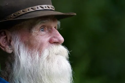 FILE — David Lidstone, 81, speaks with reporters during an interview on Tuesday, Aug. 10, 2021, in Boscawen, N.H. Lidstone, an off-the-grid New Hampshire hermit known to locals as "River Dave," had been living in a cabin in the woods along the Merrimack River, in Canterbury, N.H., for nearly three decades. A contempt of court hearing has been scheduled for Thursday, March 31, 2022, for Lidstone, accused of returning to live on property that he was ordered to stay away from. (AP Photo/Steven Se