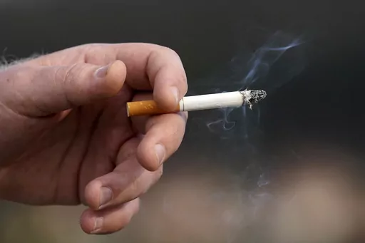 A man holds a lit cigarette while smoking, Dec. 2, 2020, in San Francisco. Brookline, Mass., has adopted an unusual smoking ban that bars tobacco sales to anyone born in the 21st century. The bylaw — the first of its kind in the country — was adopted by Brookline in 2020 and on Friday, March 8, 2024, was upheld by the state’s highest court, opening the door for other communities to adopt similar bans that will, decades from now, eventually ban all future generations from buying tobacco. (A