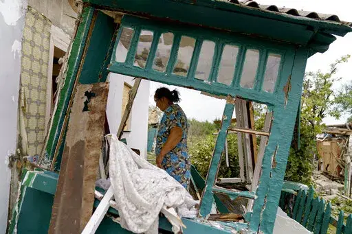 Valentyna Kondratieva, 75, walks into her damaged home Saturday, Aug. 13, 2022, where she sustained injuries in a Russian rocket attack last night in Kramatorsk, Donetsk region, eastern Ukraine. The strike killed three people and wounded 13 others, according to the mayor. The attack came less than a day after 11 other rockets were fired at the city. (AP Photo/David Goldman)
