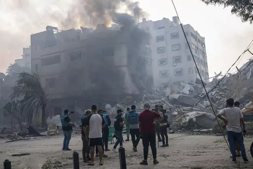 Journalists observe as Palestinians inspect the rubble of a building after it was struck by an Israeli airstrike, in Gaza City, Sunday, Oct. 8, 2023. Journalists reporting in Gaza need to worry about basic survival for themselves and their families in addition to getting out the story of a besieged population. (AP Photo/Fatima Shbair, File)