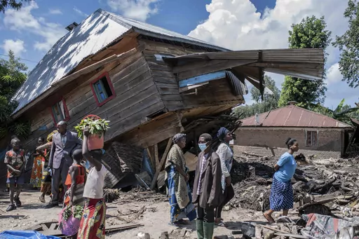 People walk next to a house destroyed by the floods in the village of Nyamukubi, South Kivu province, in Congo, Saturday, May 6, 2023. The death toll from flash floods and landslides in eastern Congo has risen according to the governor and authorities in the country's South Kivu province. (AP Photo/Moses Sawasawa)