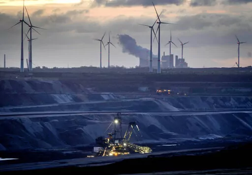 A bucket wheel excavator is mining coal at the Garzweiler open-cast coal mine with wind mills in the background in Luetzerath, Germany, Wednesday, Nov. 2, 2022. In background the coal-fired power plant Niederaussem. (AP Photo/Michael Probst)