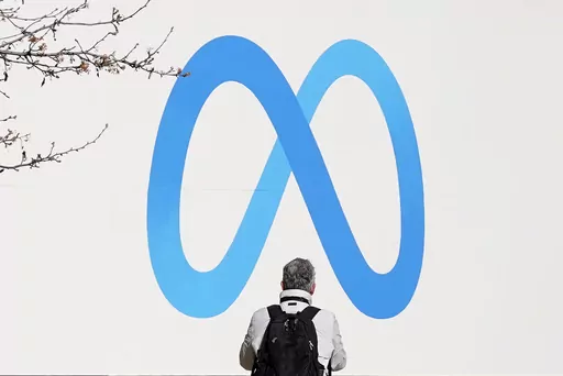 A person stands in front of a Meta sign outside of the company's headquarters in Menlo Park, Calif., Tuesday, March 7, 2023. Facebook’s parent Meta will slash another 10,000 jobs and will not fill 5,000 open positions as the social media pioneer cuts costs. (AP Photo/Jeff Chiu)