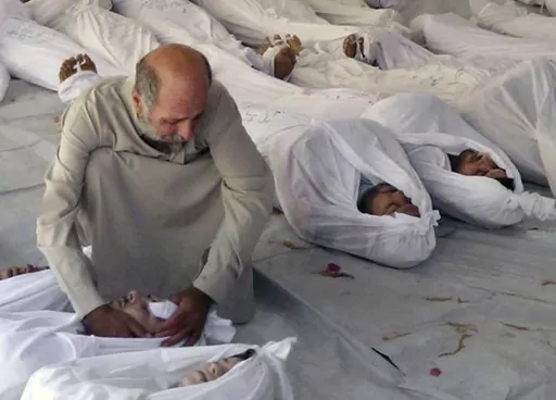 This Aug. 21, 2013 file citizen journalism image provided by the anti-government Media Office Of Douma City which has been authenticated based on its contents and other AP reporting, shows a Syrian man mourning over a dead body after an alleged poisonous gas attack fired by government forces, according to activists, in Douma town, Damascus, Syria. Syria denies ever using chemical weapons during the war and says it eliminated its chemical arsenal under a 2013 agreement brokered by the U.S. and ke