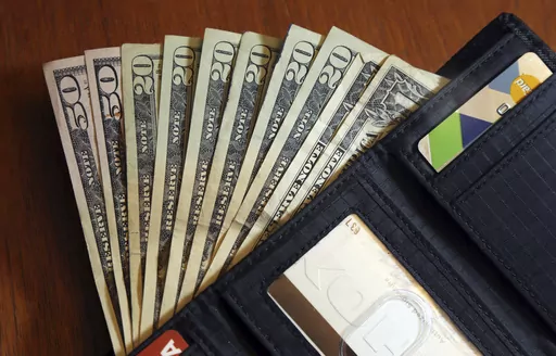 In this June 15, 2018, file photo, cash is fanned out from a wallet in North Andover, Mass. “Buy now, pay later” payment plans are a popular financing option, especially around the holiday season. But these payment plans, which divide your total purchase into a series of smaller installments that you pay back over weeks or months, aren’t always the best choice for shoppers. (AP Photo/Elise Amendola, File)