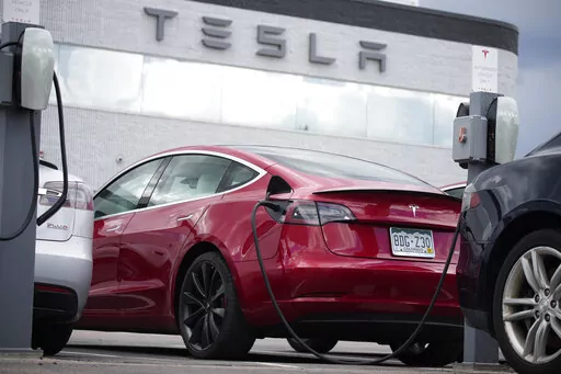 In this Sunday, June 27, 2021, photograph, a 2021 Model 3 sedan sits in a near-empty lot at a Tesla dealership in Littleton, Colo.   A build-to-order vehicle from the factory ensures you get the exact car, color and option combination that you want. It’s a little-known method to save time tracking down a vehicle that fits your needs.  (AP Photo/David Zalubowski)