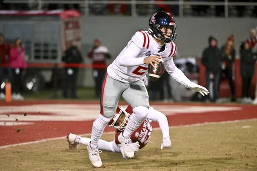 Mississippi quarterback Jaxson Dart (2) tries to get away from Arkansas defensive lineman Jashaud Stewart (58) during the first half of an NCAA college football game Saturday, Nov. 19, 2022, in Fayetteville, Ark. (AP Photo/Michael Woods)