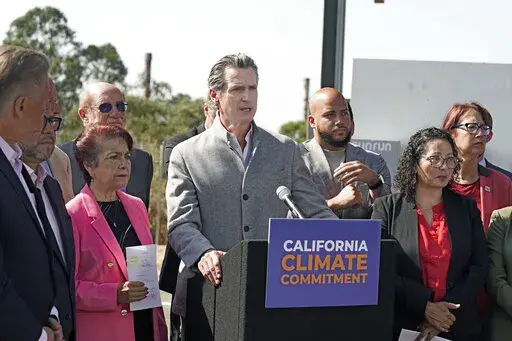 Gov. Gavin Newsom, center, is flanked by state lawmakers while discussing the package of legislation he signed that accelerates the climate goals of the nation's most populous state, at Mare Island in Vallejo, Calif., Friday, Sept. 16, 2022. Newsom opposes Proposition 30, which would raise taxes on people making more that $2 million to pay for electric vehicle infrastructure and firefight resources. (AP Photo/Rich Pedroncelli, File)