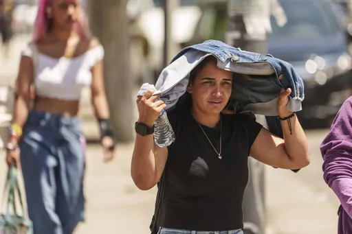 Sorelly Restrepo, of Colombia, shields herself from the sunlight in the Little Tokyo district of Los Angeles, July 27, 2023. Across the U.S., many people are living through one of the most brutal summers of their lives and reckoning with the idea that climate change is only going to make matters worse in the coming decades. (AP Photo/Damian Dovarganes, File)