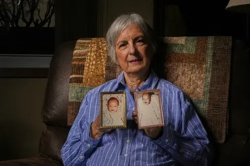 Peg Reif holds pictures of her children adopted from South Korea in the 1980s in her home Tuesday, Dec. 17, 2024 in Platteville, Wis. (AP Photo/Morry Gash)