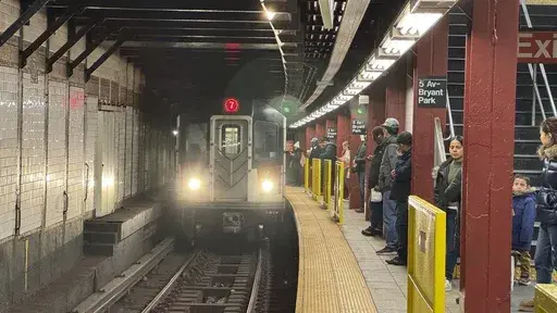 Subway riders stand near yellow barriers on a platform of the 7 train in New York on Tuesday, March 26, 2024. (AP Photo/Cedar Attanasio, File)