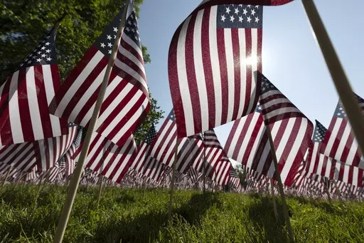 The sun shines through the flags in the Memorial Day Flag Garden on Boston Common, May 27, 2023, in Boston. Memorial Day is supposed to be about mourning the nation’s fallen service members. But it’s come to anchor the unofficial start of summer and retail discounts. (AP Photo/Michael Dwyer, file)