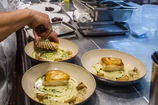 A worker arranges food onto plates in the kitchen of a restaurant in New York on Dec. 14, 2021. Food workers who showed up while sick or contagious were linked to about 40% of restaurant food poisoning outbreaks with a known cause between 2017 and 2019, federal health officials said Tuesday, May 30, 2023. (AP Photo/Brittainy Newman, File)