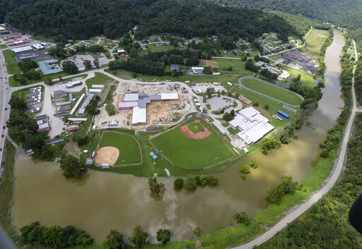 In this aerial image, the river is still high around the homes in Breathitt County, Ky., on Saturday, July 30, 2022. Recovery has begun in many of the narrow hollers after historic rains flooded many areas of Eastern Kentucky killing more at least two dozen people. A layer of mud from the retreating waters covers many cars and homes. (Michael Clevenger/Courier Journal via AP)