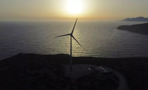 The sun sets behind a wind turbine on the Aegean Sea island of Tilos, southeastern Greece, Monday, May 9, 2022. When deciding where to test green tech, Greek policymakers picked the remotest point on the map, tiny Tilos. Providing electricity and basic services, and even access by ferry is all a challenge for this island of just 500 year-round inhabitants. It's latest mission: Dealing with plastic. (AP Photo/Thanassis Stavrakis)