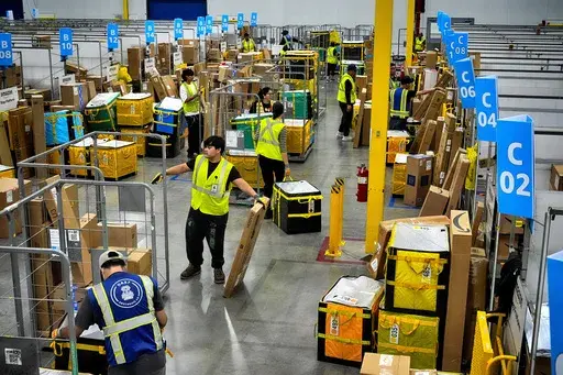 Amazon employees load packages on carts before being put on to trucks for distribution for Amazon's annual Prime Day event at an Amazon's DAX7 delivery station on Tuesday, July 16, 2024, in South Gate, Calif. (AP Photo/Richard Vogel, File)